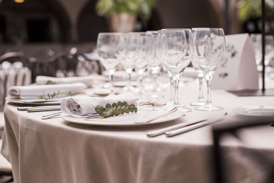 Elegante mesa de banquete puesta con platos blancos, servilletas dobladas, cubiertos y copas de vino