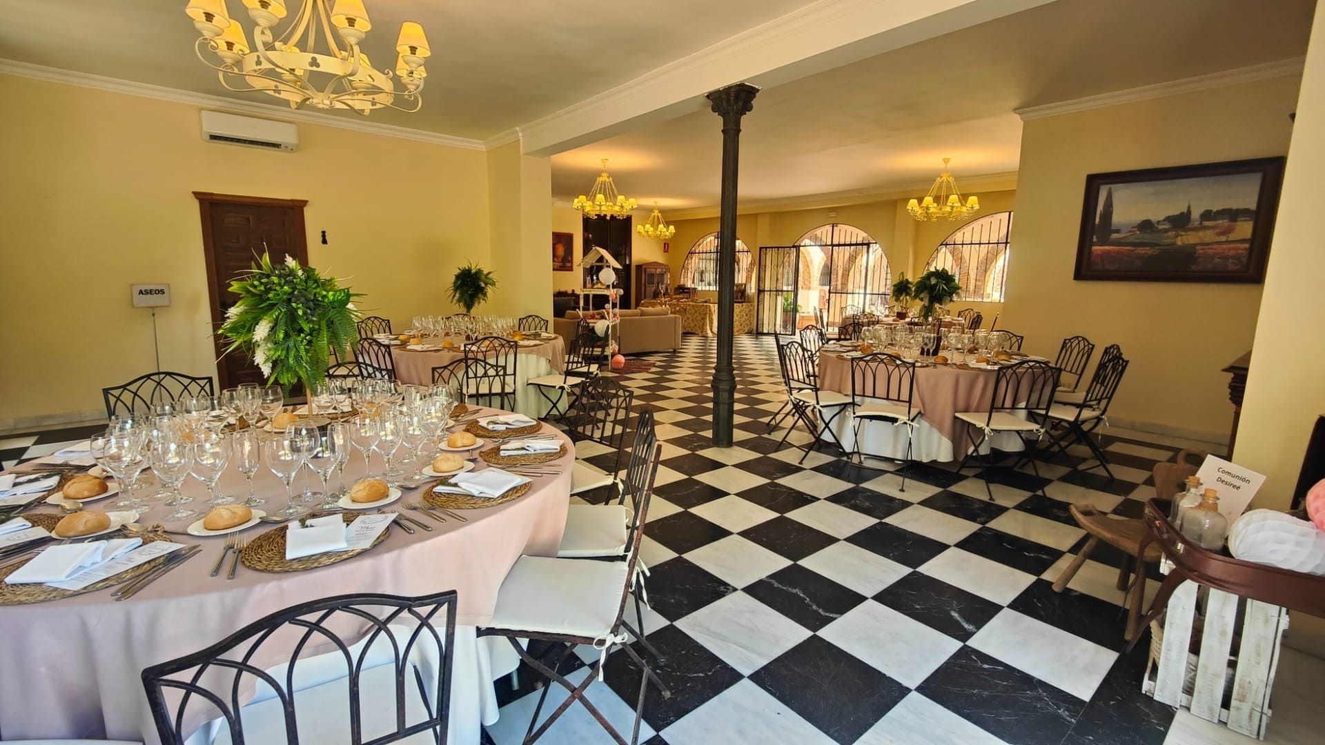 Elegante salón de banquetes con mesas preparadas, lámparas de araña y suelo de cuadros blancos y negros