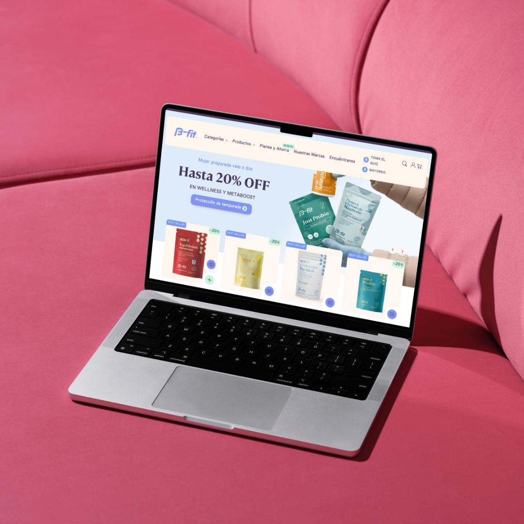 Computadora portátil sobre un sofá rosa que muestra un sitio web con imágenes de productos