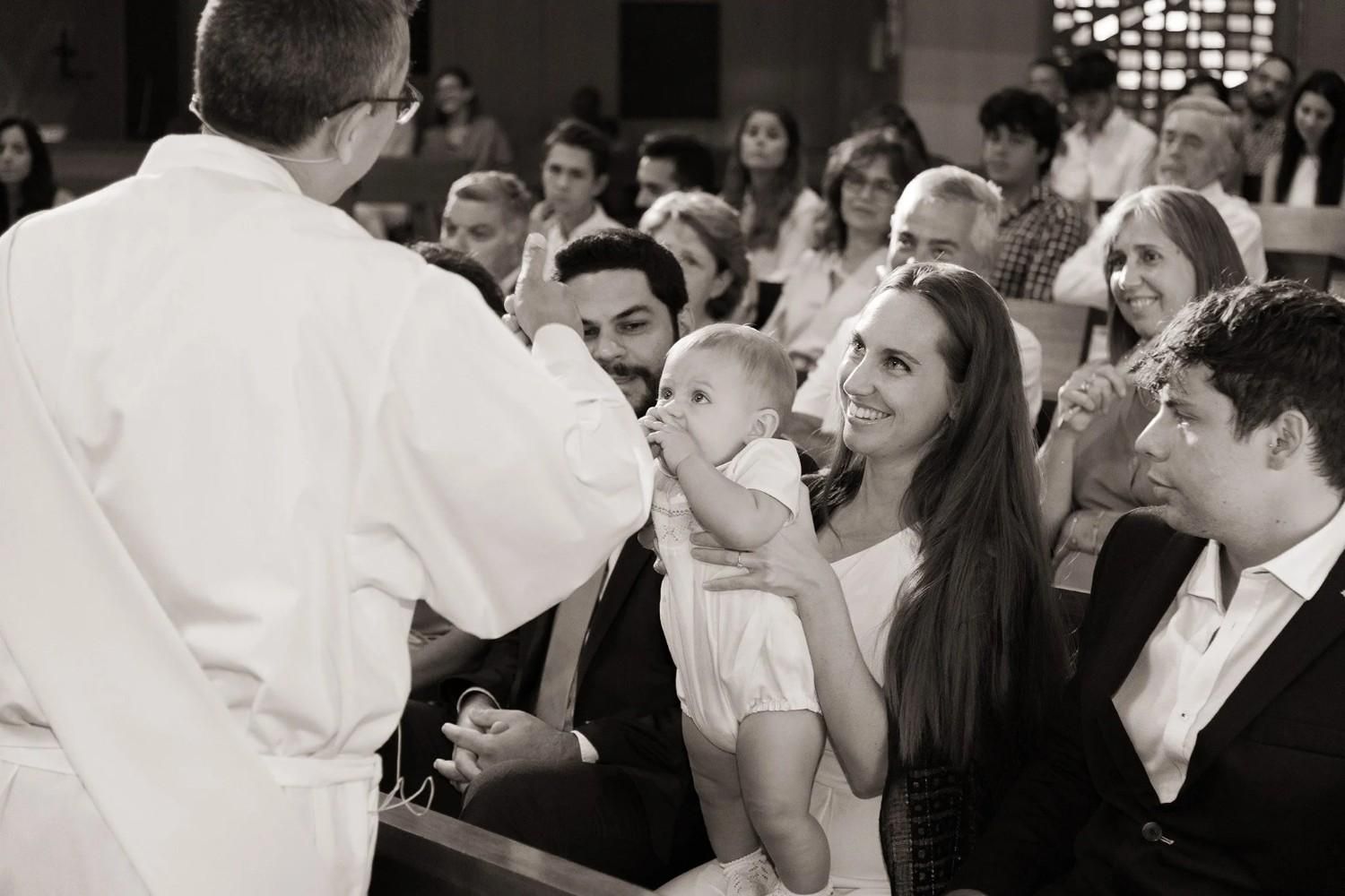 Un hombre se dirige a un público sentado en una iglesia, mientras la gente sonríe y escucha atentamente.