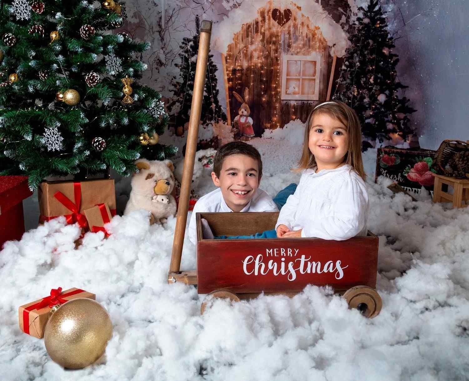 Niños en una escena fotográfica navideña junto a un trineo con la inscripción 