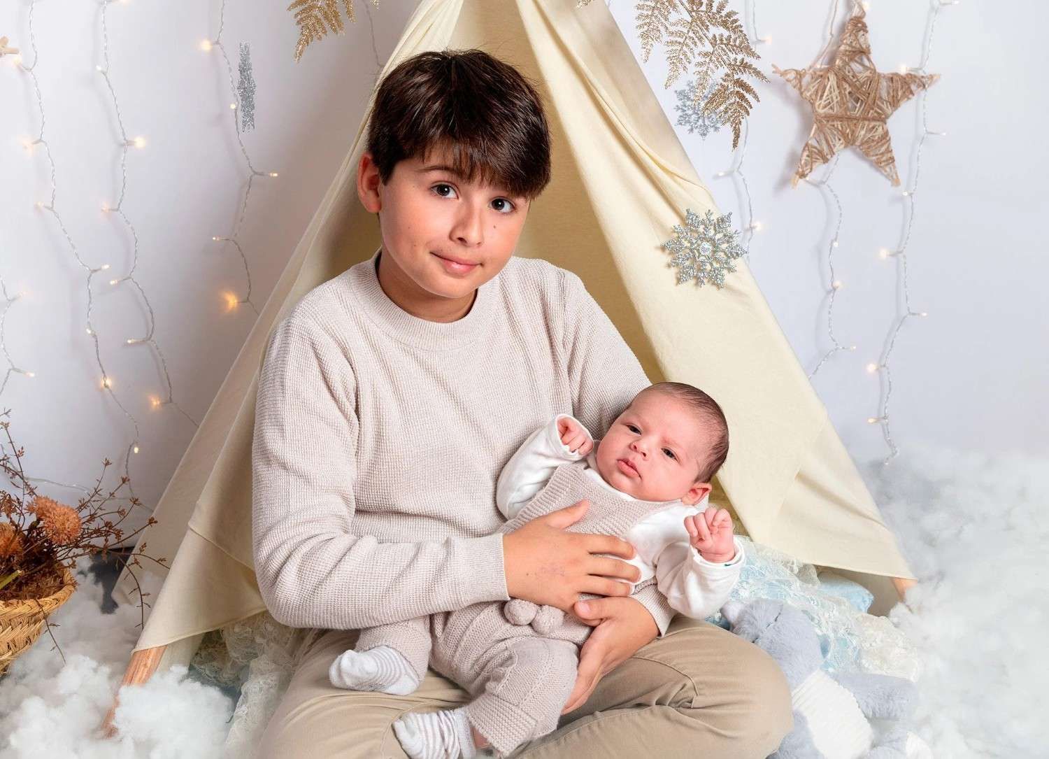 Una persona sostiene a un bebé en una fotografía tomada en un ambiente suave y estrellado en interiores.