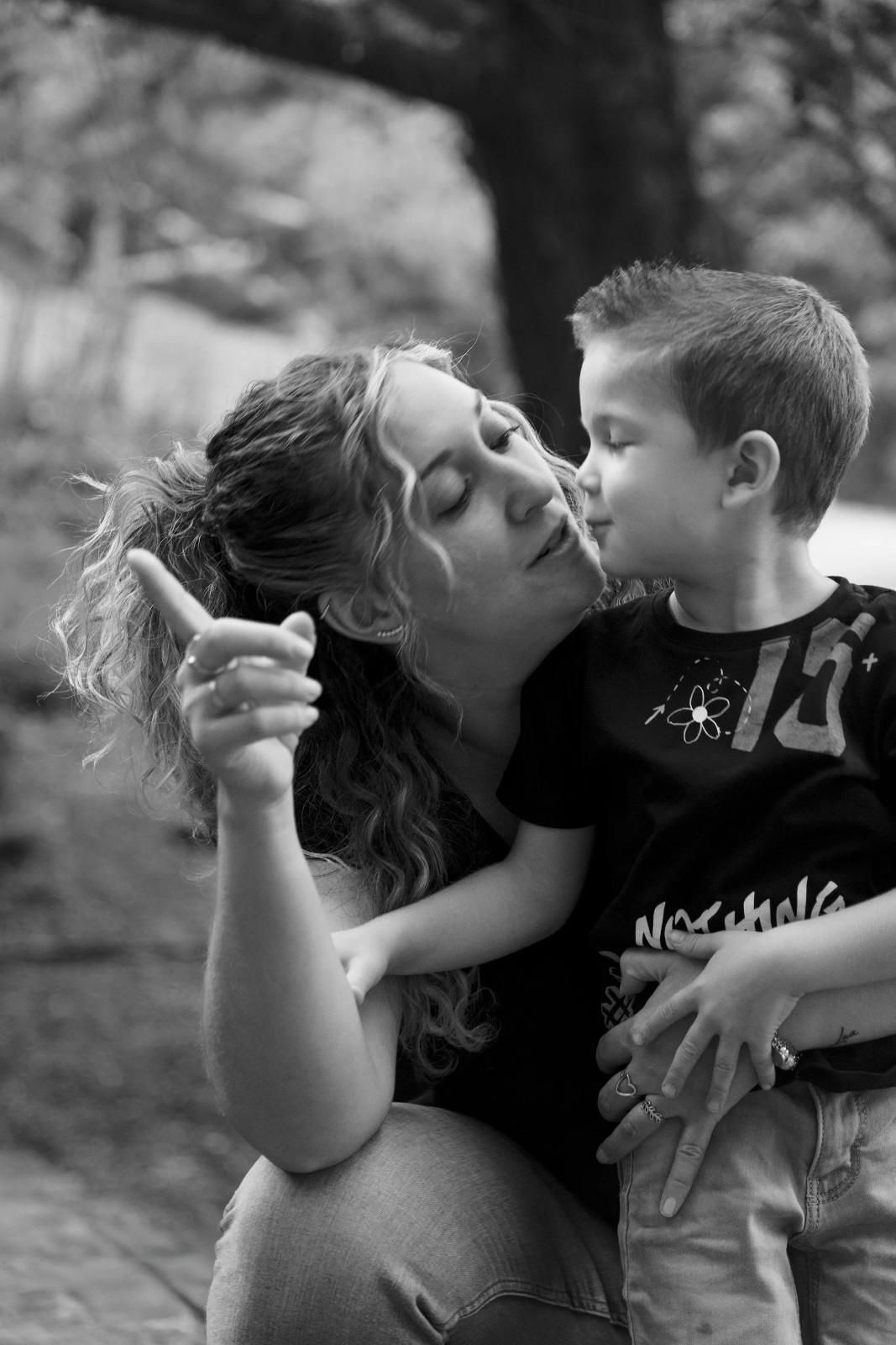 Mujer besando a un niño al aire libre mientras sostiene un cigarrillo.