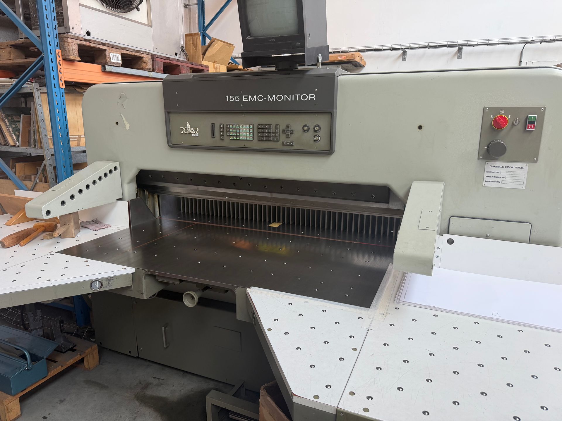 Une grande machine à découper le papier avec une feuille de papier jaune en position de découpe.
