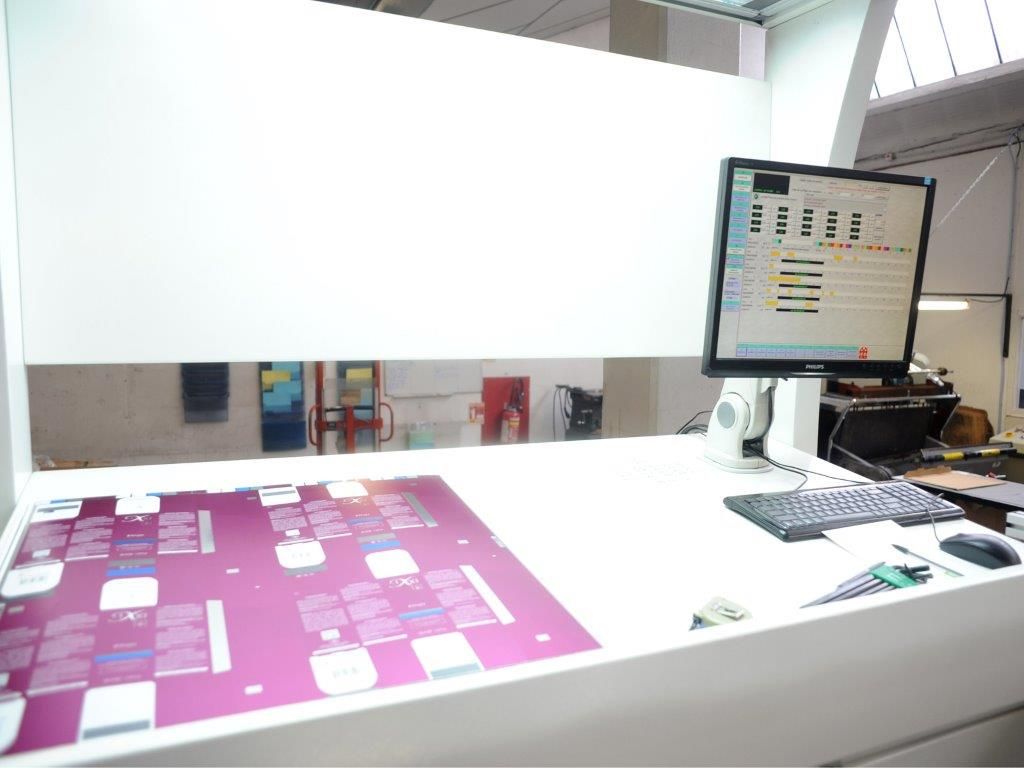 Un panneau de commande comprenant un écran d'ordinateur, un clavier et le schéma d'une plaque d'impression.