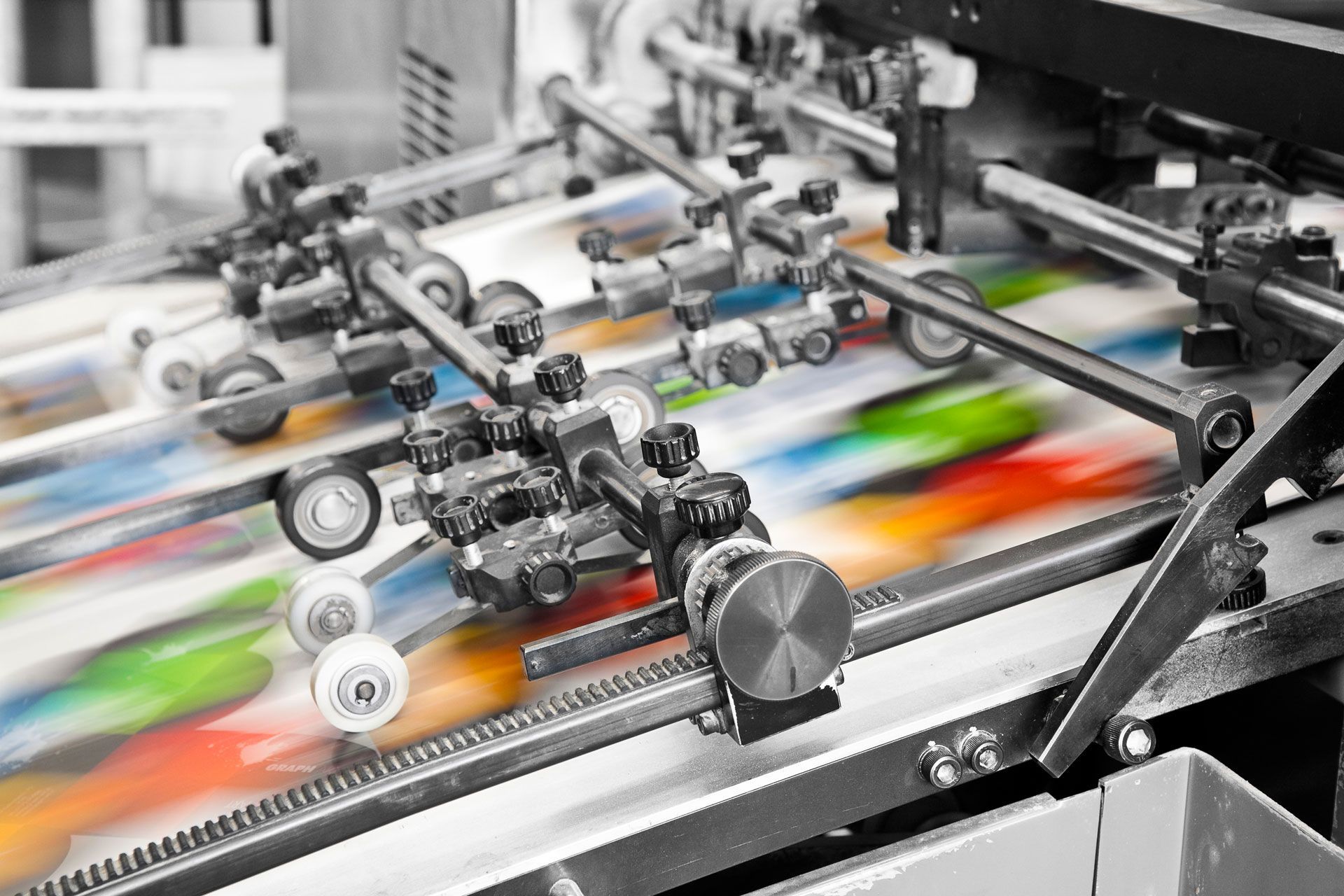 Presse à imprimer en fonctionnement, avec des images colorées qui défilent sur des tapis roulants.