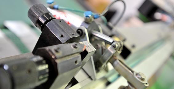 Gros plan sur des machines industrielles ; bras robotisés manipulant une pièce métallique, processus de fabrication.