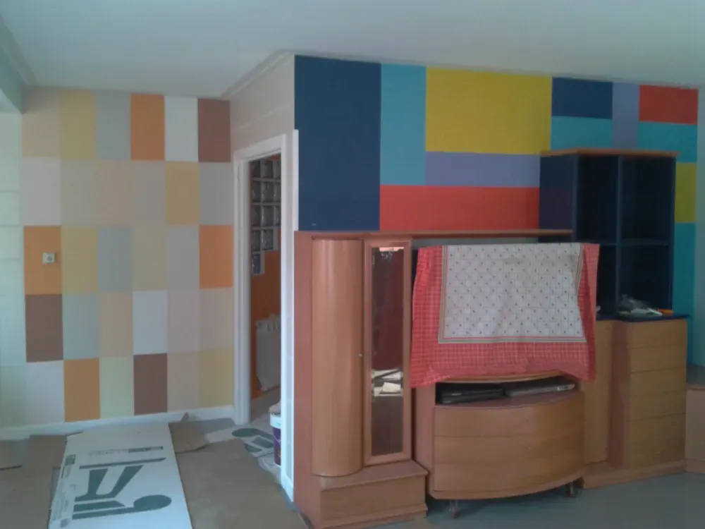 Habitación con pintura geométrica colorida en la pared. Muebles de madera en el centro.