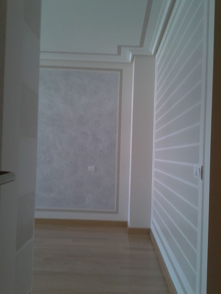 Un pasillo con paredes blancas y suelos de madera.