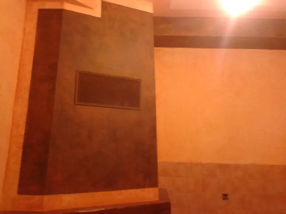 Pared interior con sección texturizada de color marrón oscuro, con panel rectangular y paredes de color naranja claro.