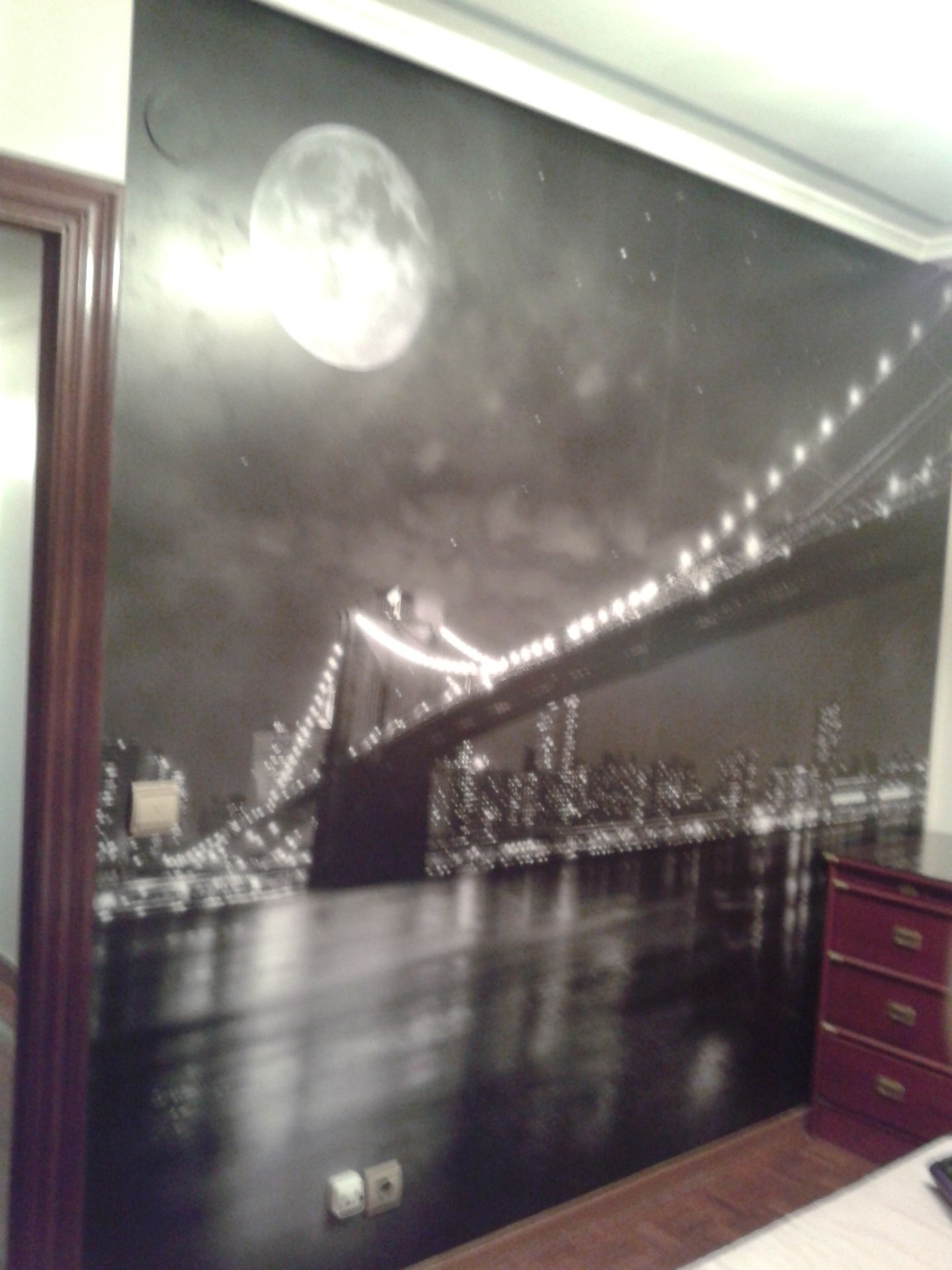 Una fotografía en blanco y negro de un puente con una luna llena al fondo.