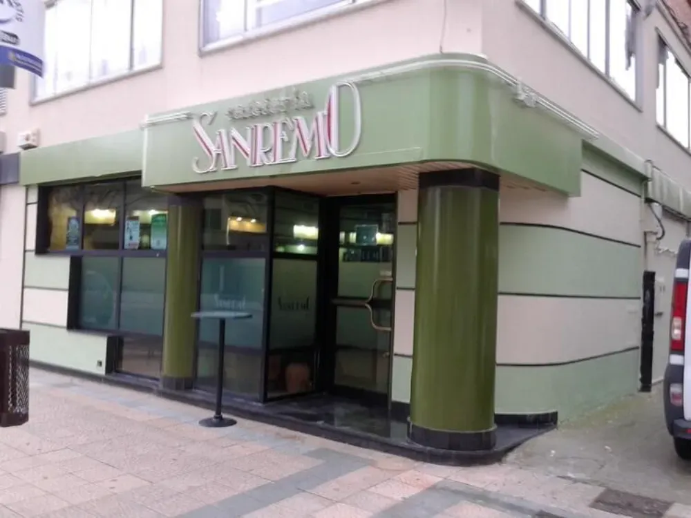 Exterior del restaurante italiano San Remo con fachada verde y blanca. Ventanales y entrada de cristal.