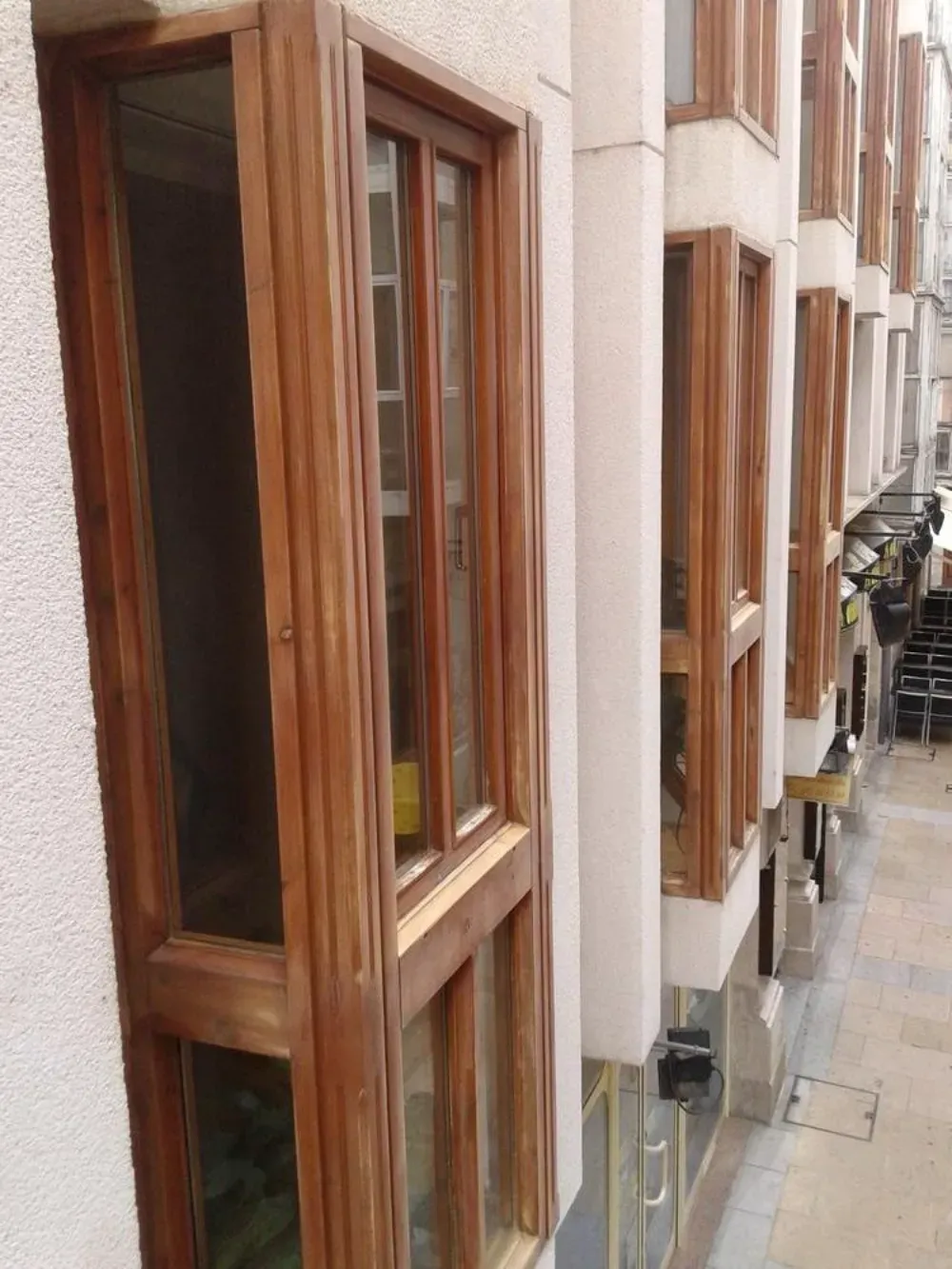 Marcos de ventanas de madera a lo largo de la fachada de un edificio, vista de la calle abajo.
