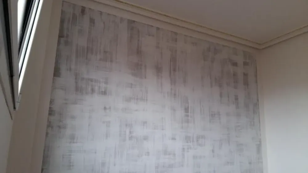 Pared interior con diseño texturizado en gris y blanco, bordeada por moldura blanca.