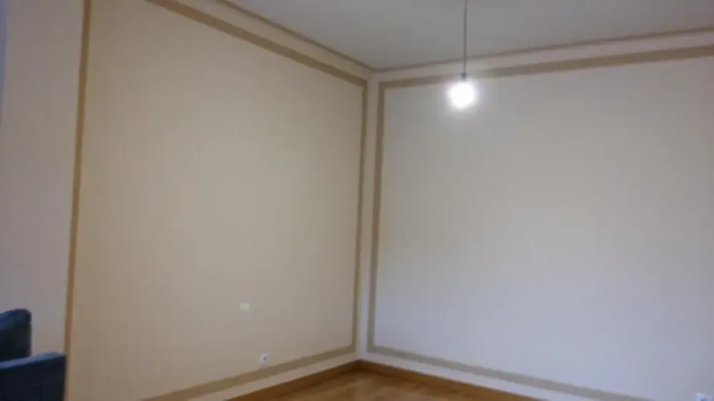 Habitación vacía con paredes de color beige, molduras y lámpara de color marrón.