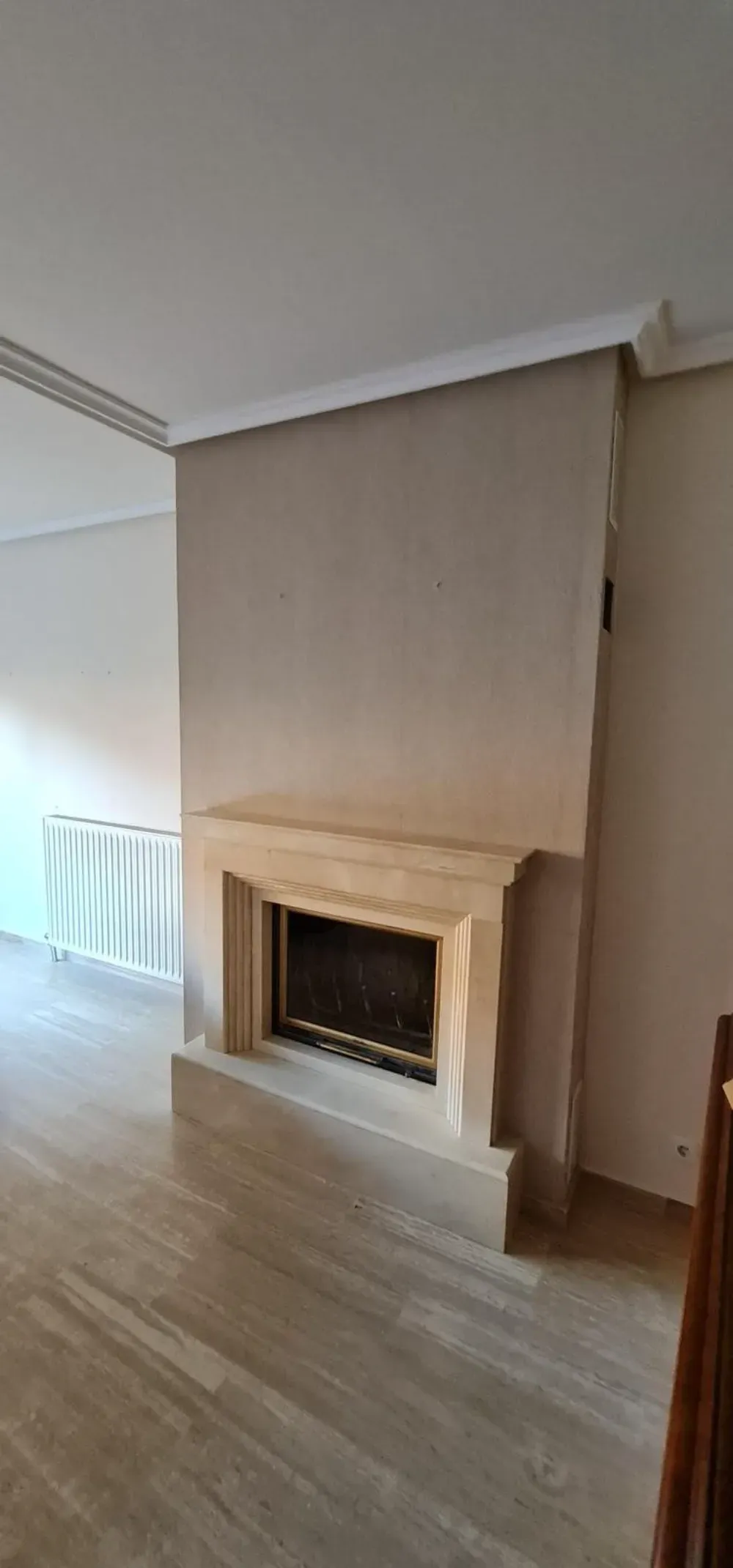 Una chimenea con repisa de piedra en una habitación con paredes y suelos de colores claros.