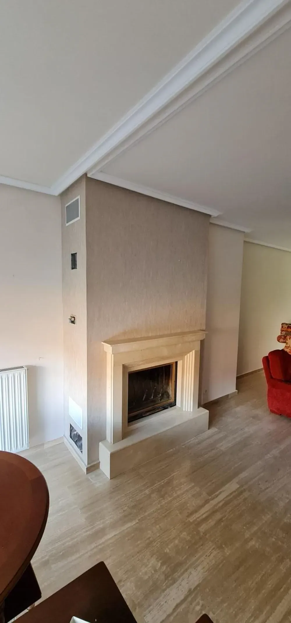 Chimenea en una habitación con paredes y suelo de color claro y un sillón rojo.