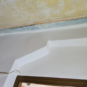 Una pared blanca con una puerta al fondo.