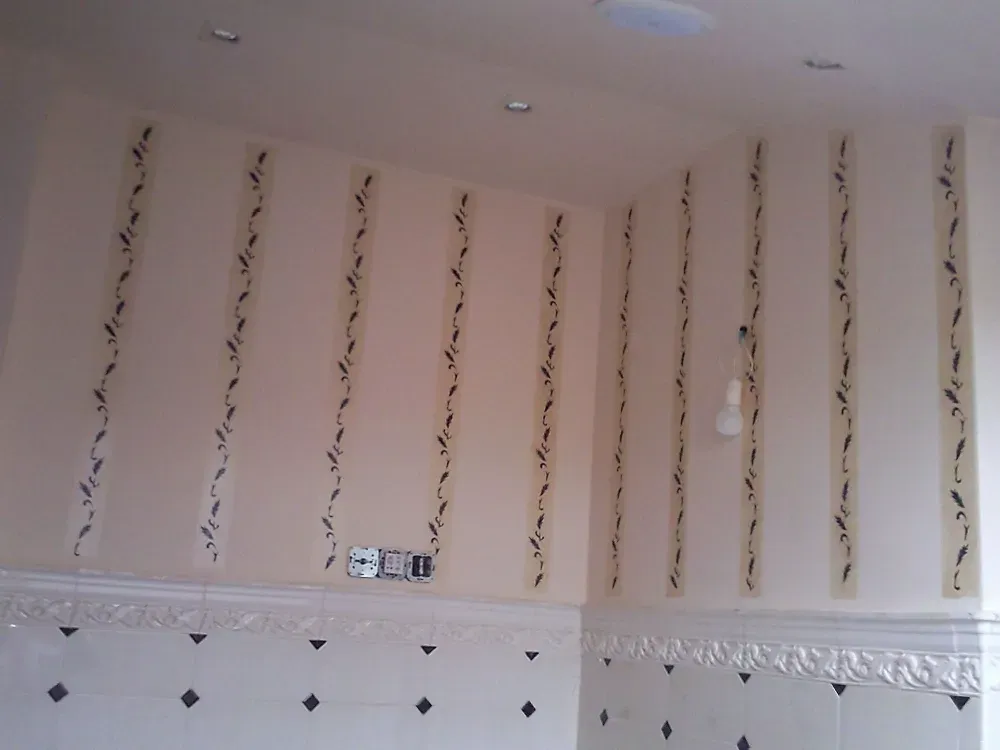 Paredes de color crema con rayas verticales con motivos florales, sobre una pared de azulejos blancos y un suelo de azulejos