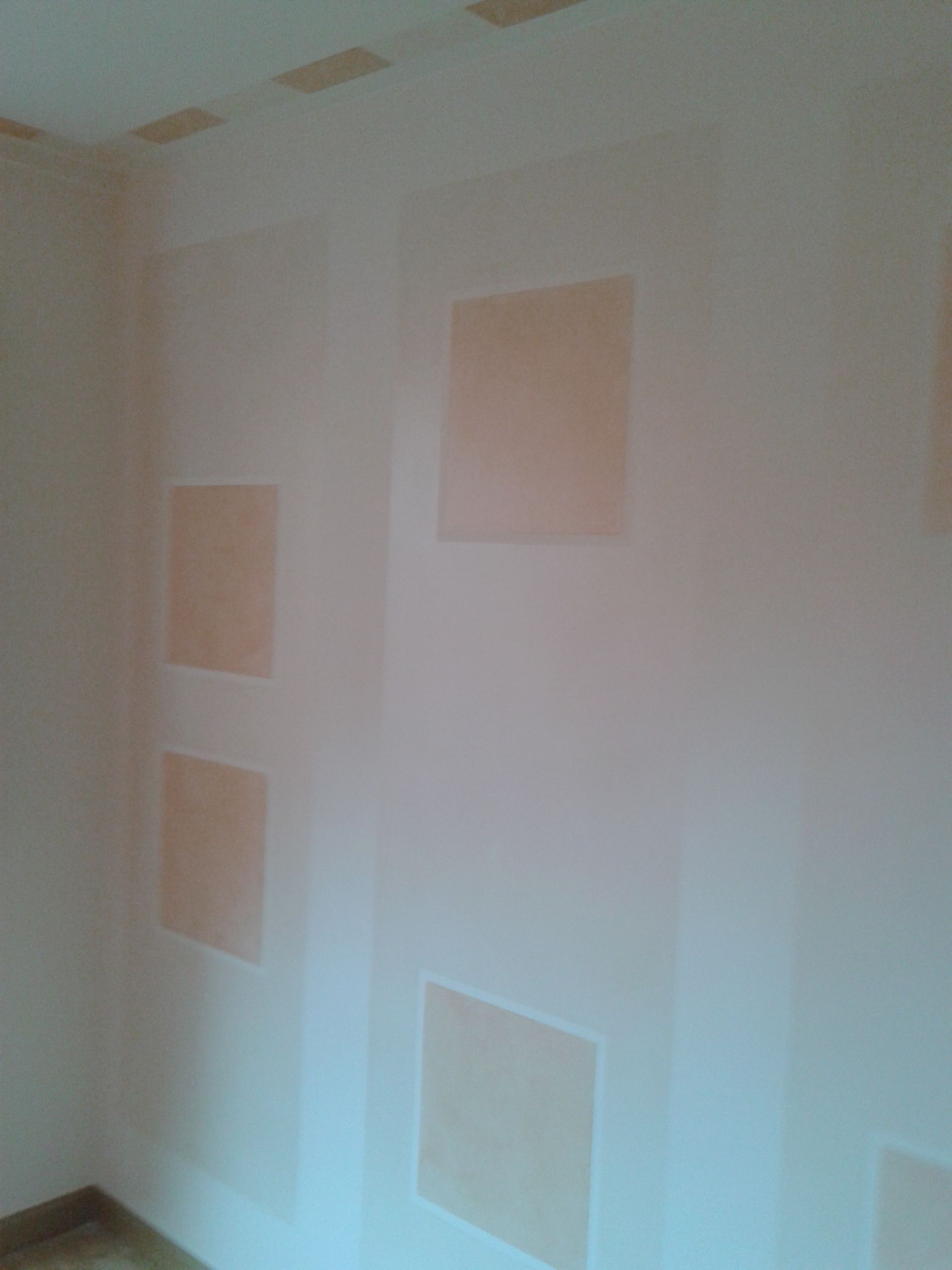 Una habitación con una pared blanca y tres cuadrados en ella.