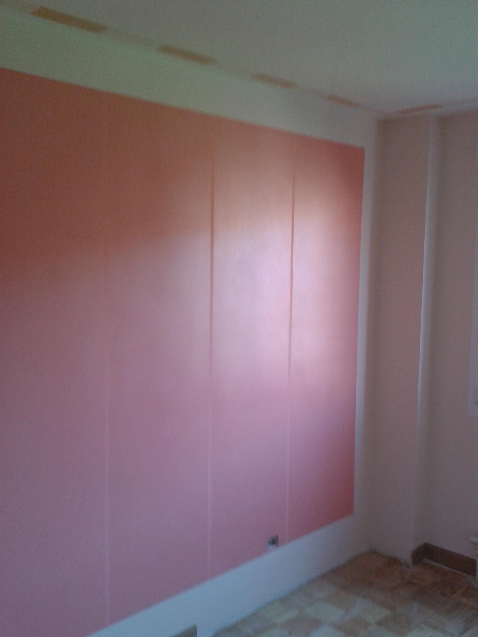 Una habitación con una pared rosa y un suelo de baldosas.