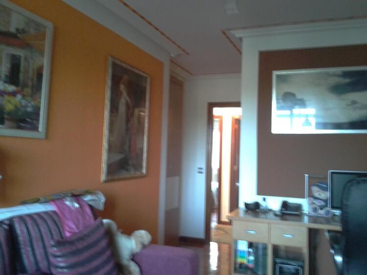 Una sala de estar con paredes naranjas y un sofá morado.