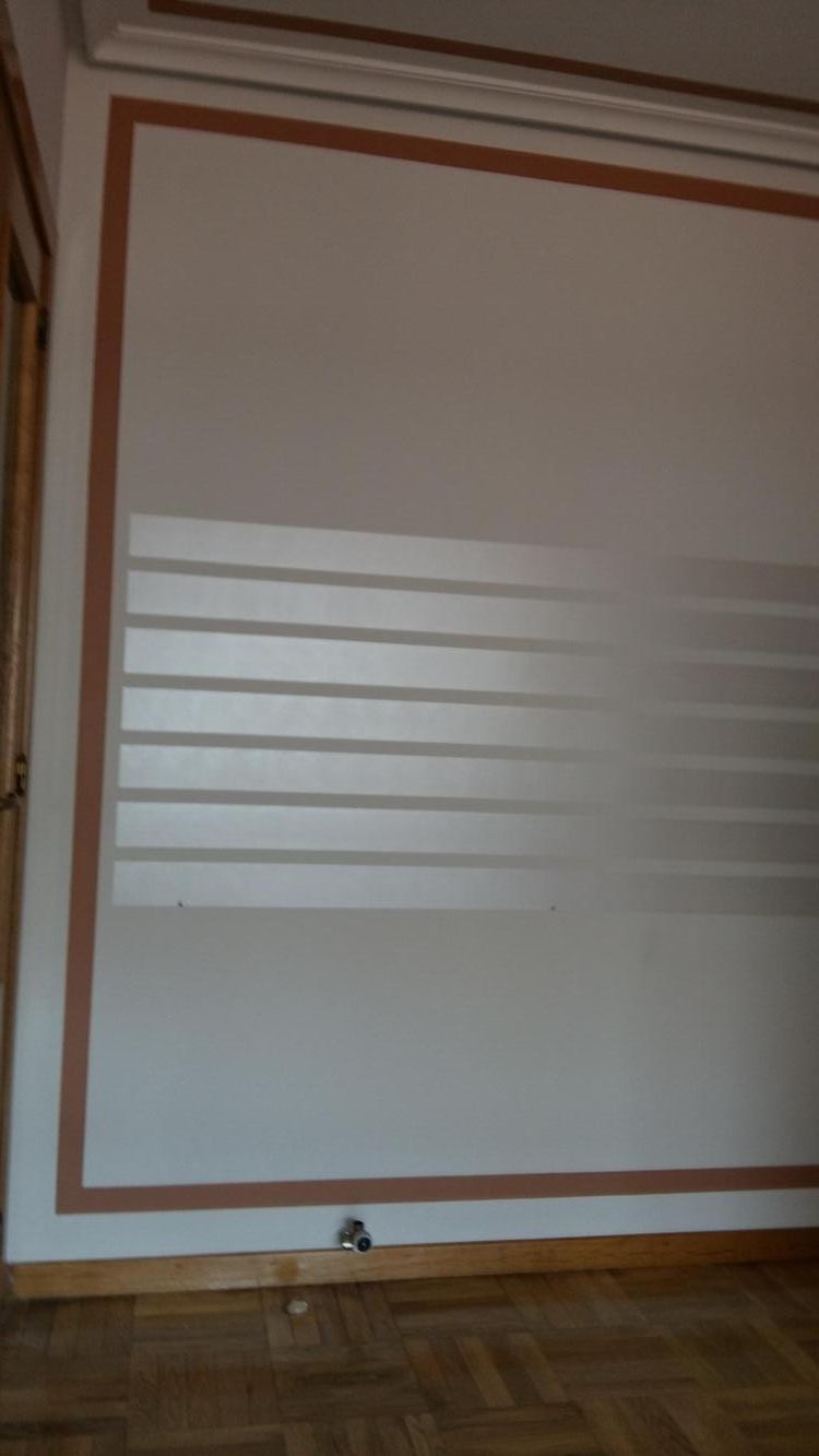 Una pared blanca con un marco marrón y un piso de madera en una habitación.