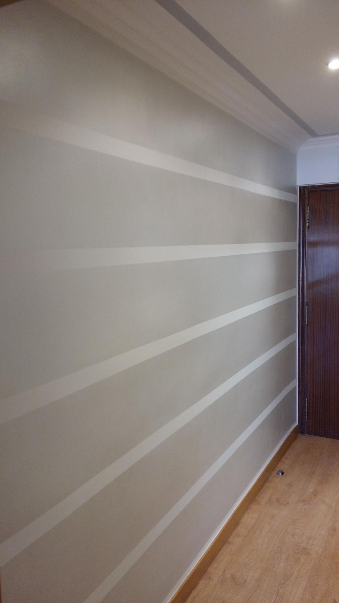 Un pasillo con una pared rayada y una puerta de madera.