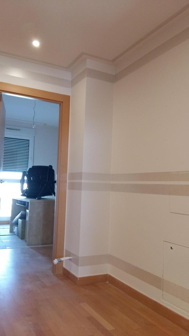 Un pasillo con paredes blancas y pisos de madera que conduce a una sala de estar.