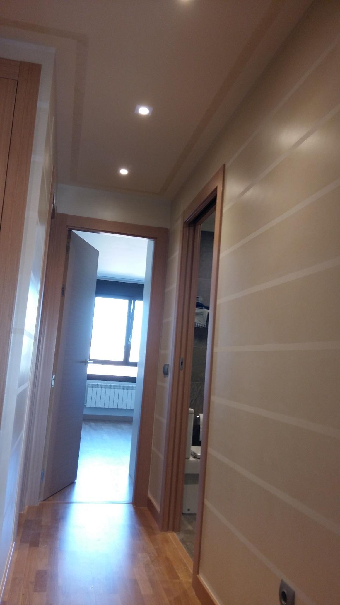 Un pasillo con suelo de madera y paredes blancas.