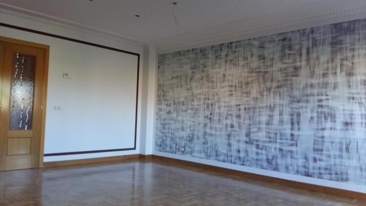 Una sala de estar vacía con un cuadro grande en la pared.