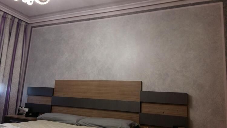 Un dormitorio con una cama, mesita de noche y lámpara de araña.