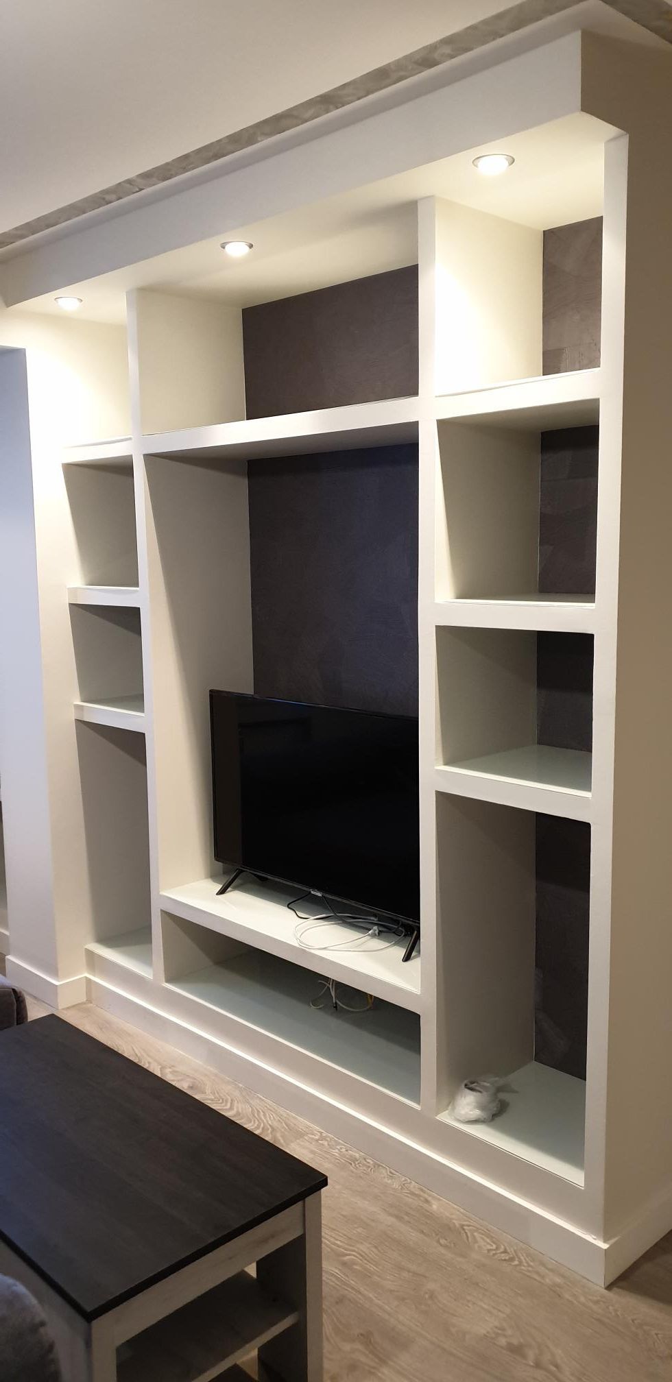 Una sala de estar con un televisor en un soporte y una mesa de café.