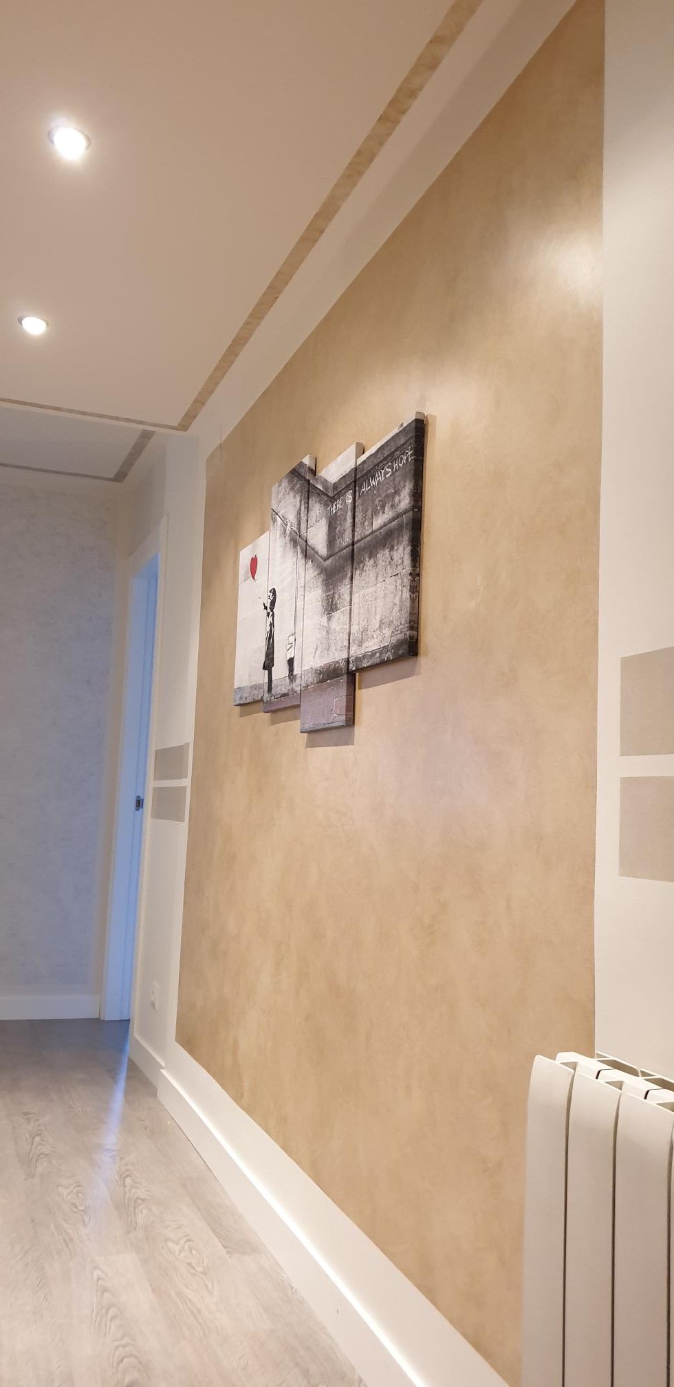 Un pasillo con un cuadro en la pared y un radiador.