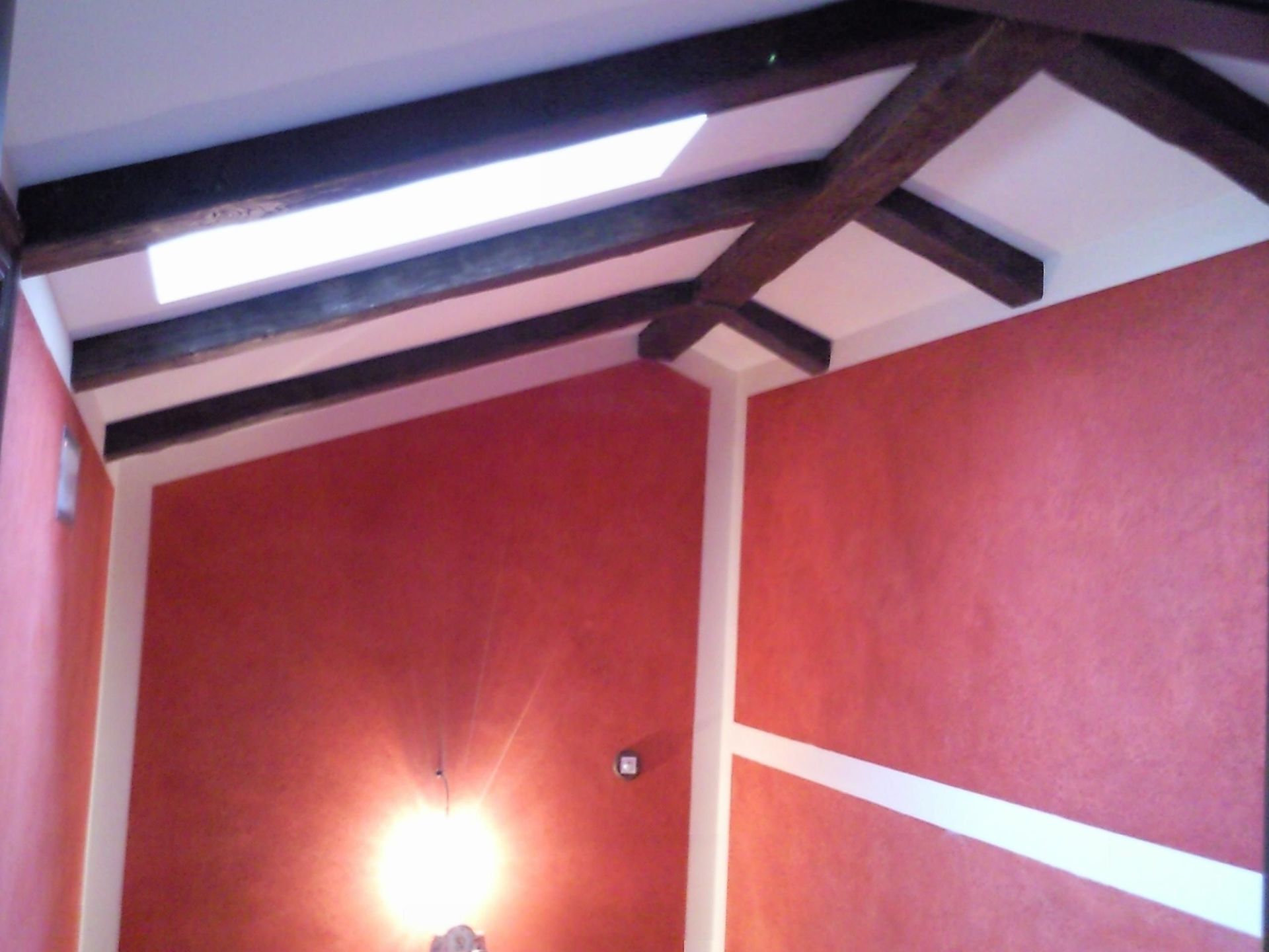 Una habitación con paredes rojas y vigas de madera en el techo.