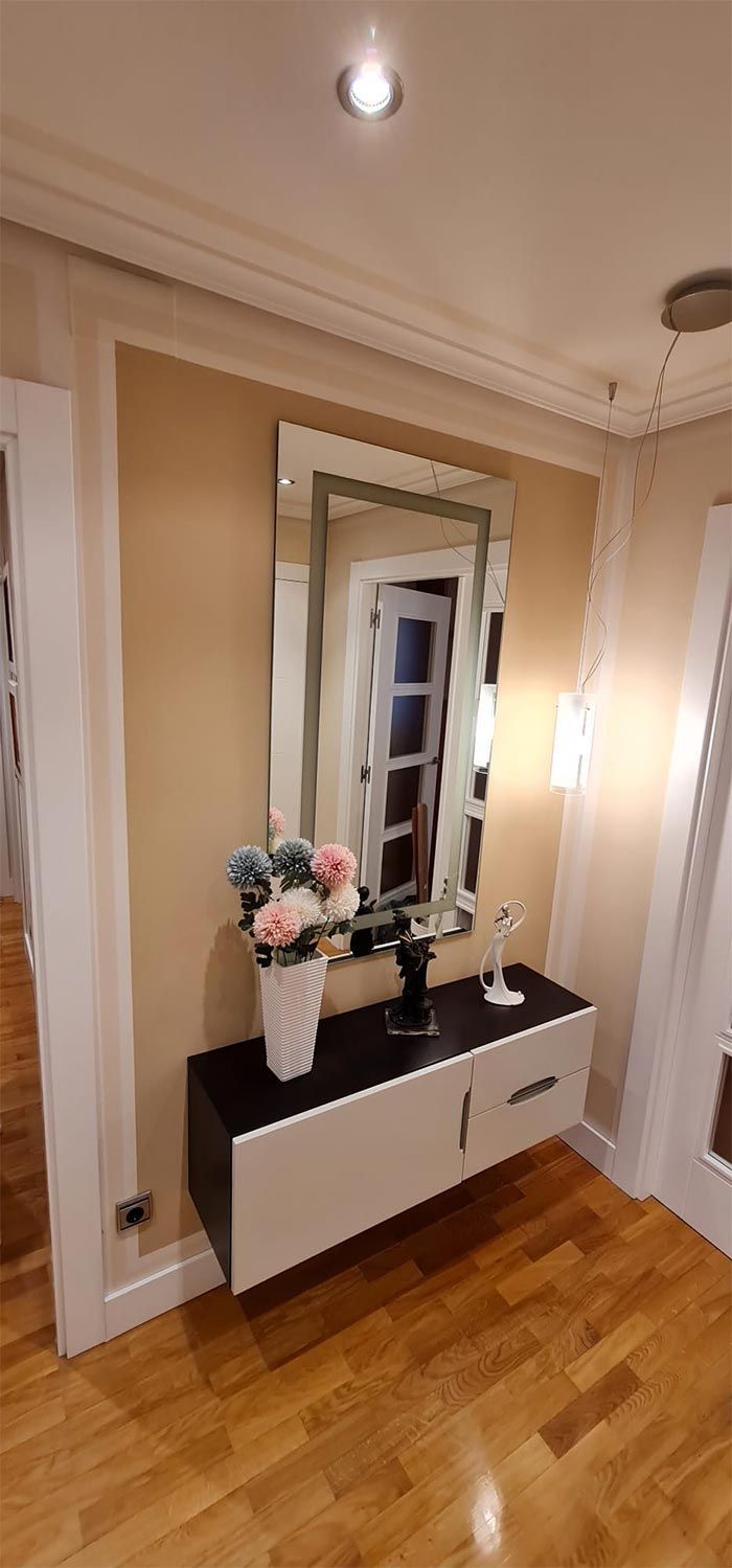 Un pasillo con un espejo y una mesa con flores.