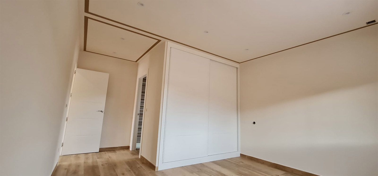 Una habitación vacía con paredes blancas y suelos de madera.