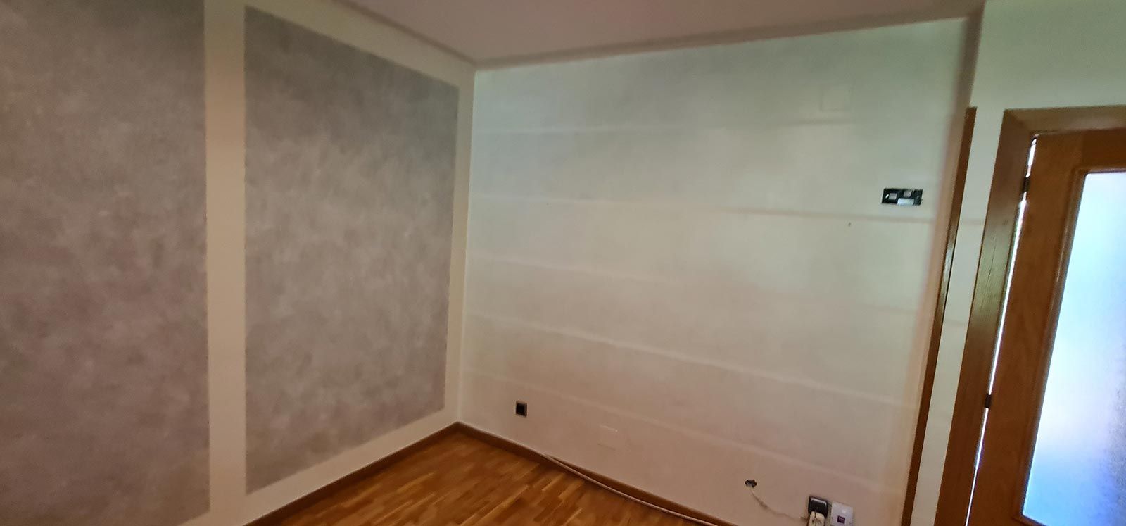 Una habitación con paredes blancas y suelo de madera.