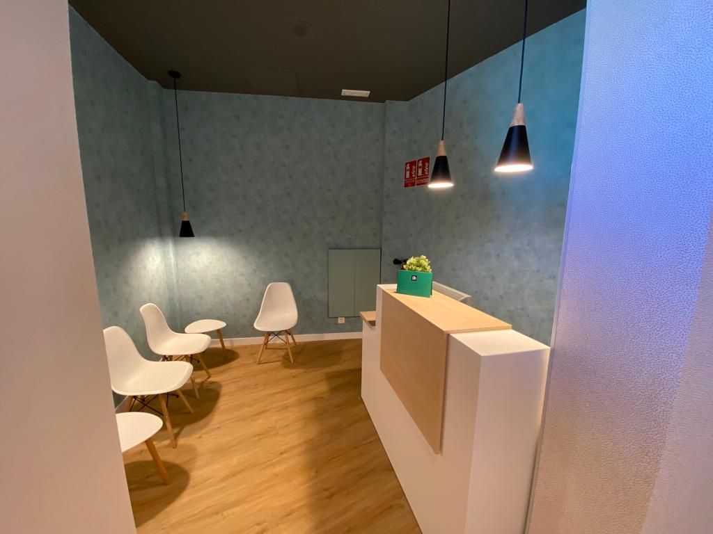Una sala de espera con un mostrador de recepción y sillas.