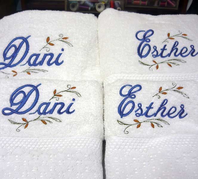Cuatro toallas blancas con los nombres Dani y Esther bordados en ellas.