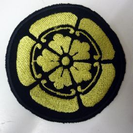 Un parche negro con una flor amarilla bordada en él.
