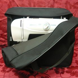 Una máquina de coser blanca está en una bolsa negra