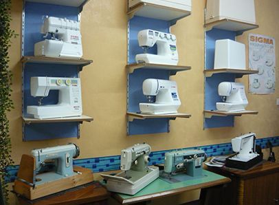 Varias máquinas de coser están alineadas en los estantes de una tienda.