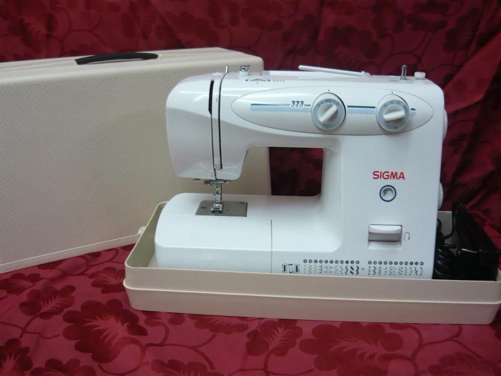 Una máquina de coser Sigma blanca se encuentra sobre una mesa.