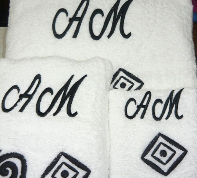 Tres toallas blancas con las letras acm bordadas en ellas