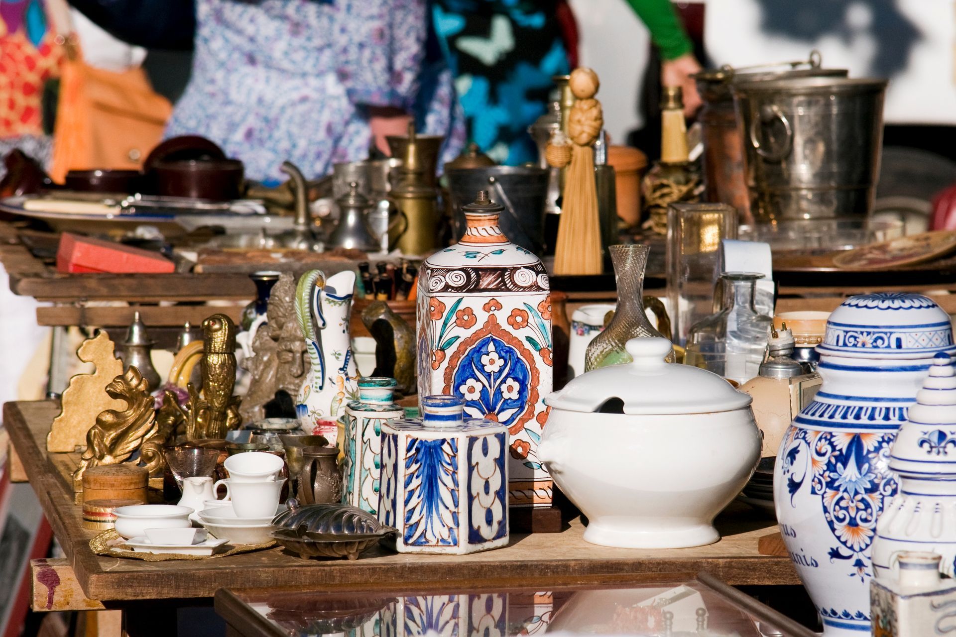 Divers objets anciens en céramique bleue et blanche et en métal sont exposés sur une table.