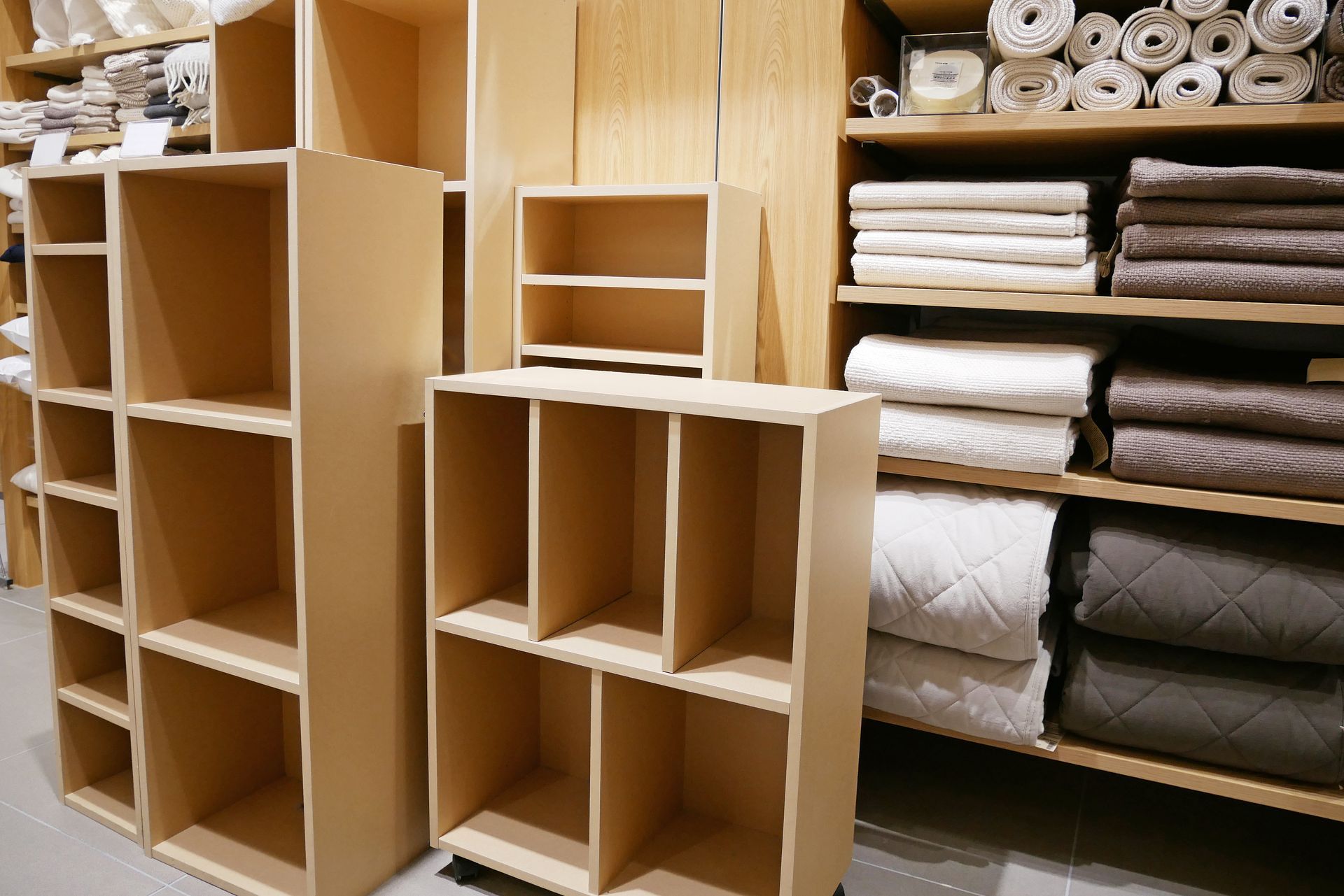 Étagères en bois avec des tissus pliés et des matériaux enroulés dans un magasin ou un atelier.