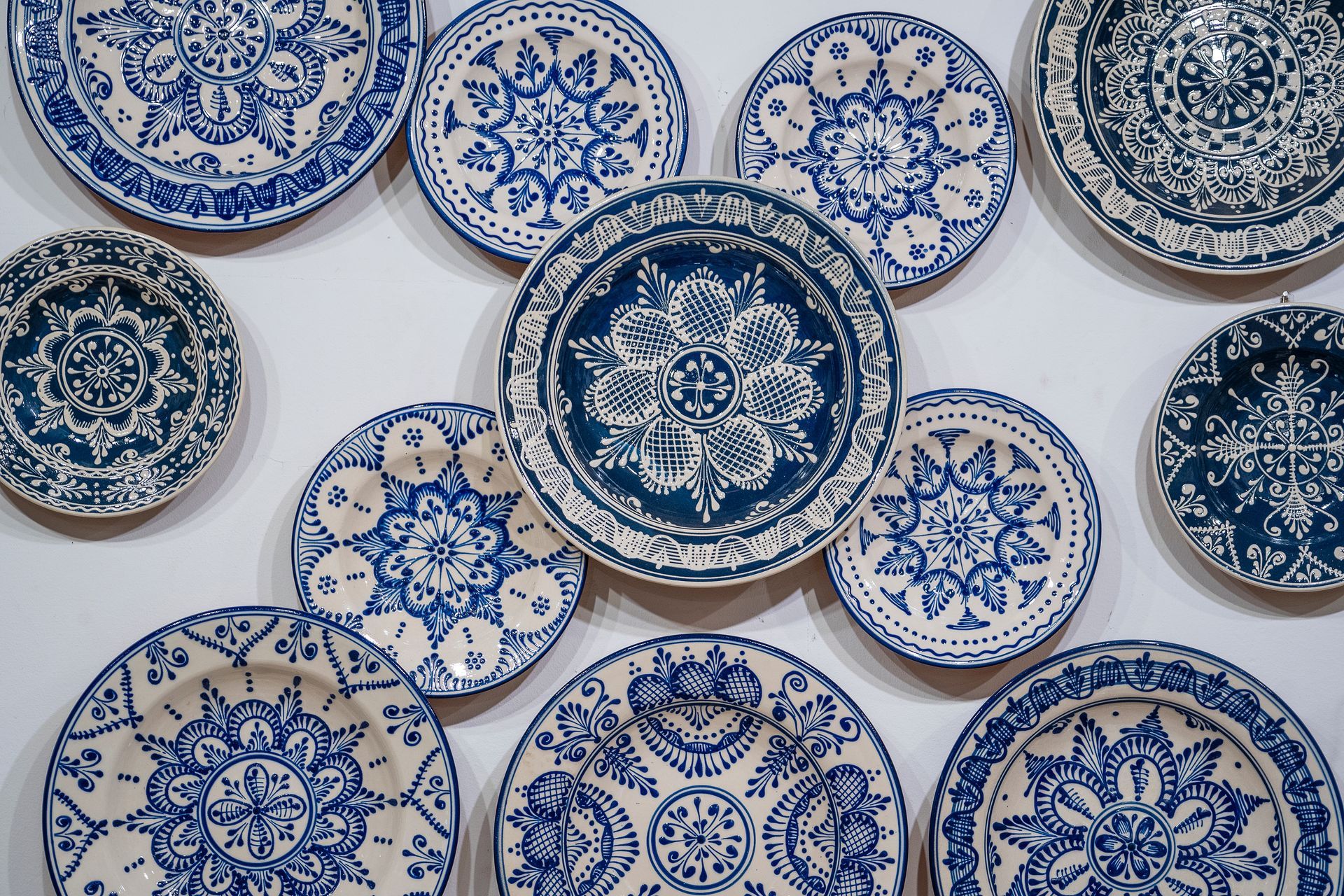 Assiettes en céramique à motifs bleus et blancs disposées de manière décorative sur un fond blanc
