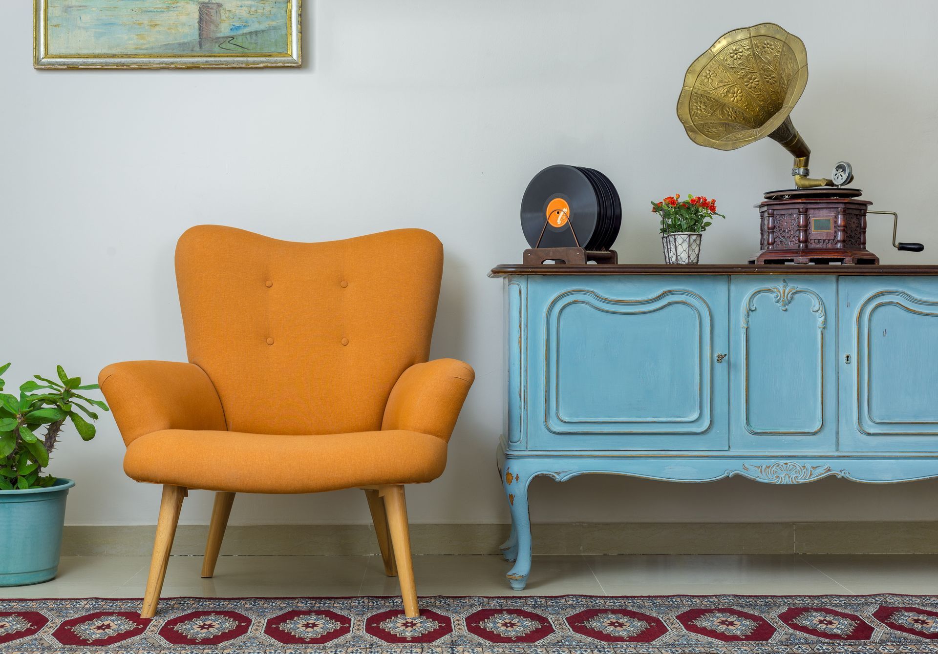 Fauteuil orange à côté d'un buffet bleu avec un gramophone et des objets de décoration dans une pièce confortable