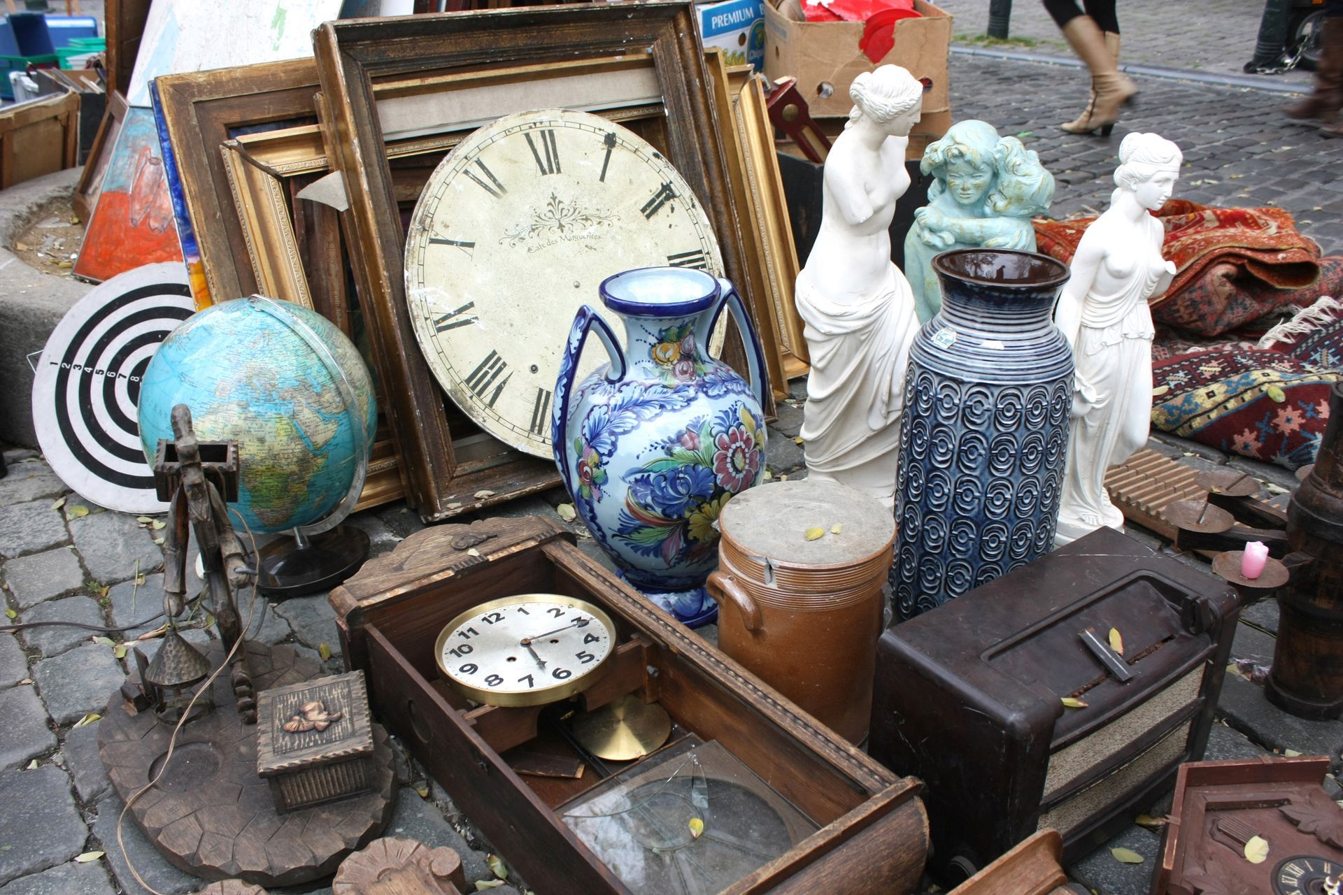 Assortiment d'horloges, de globes et d'objets décoratifs anciens sur un étal en plein air